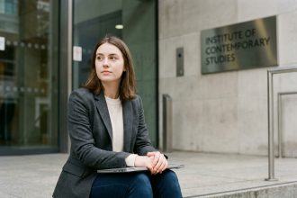 Jeune femme pensif assise devant une universite moderne